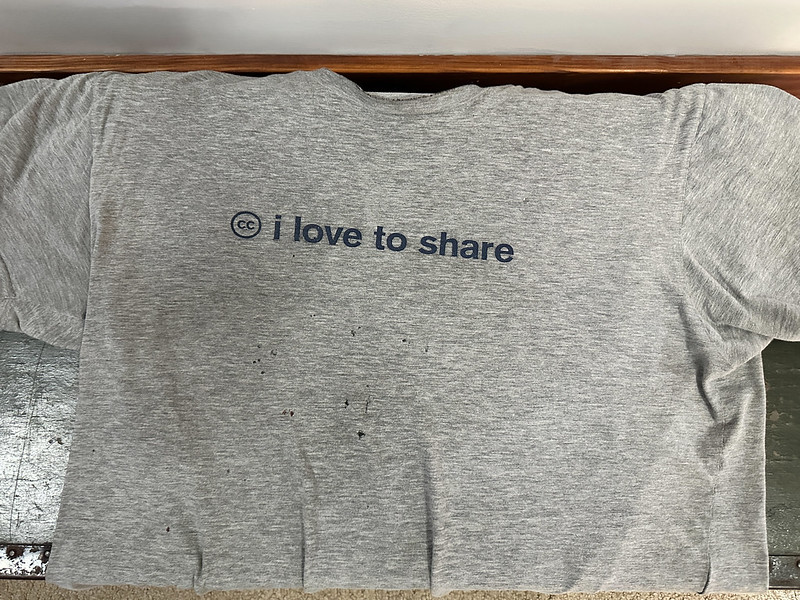 Greey shirt with a few hole and the Creative Commons "CC" logo and words "We love to share."